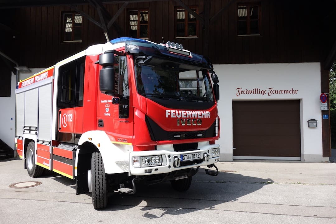 Das HLF 10 der Feuerwehr Traubing vor dem Feuerwehrhaus, an der Wand der Schriftzug „Freiwillige Feuerwehr“